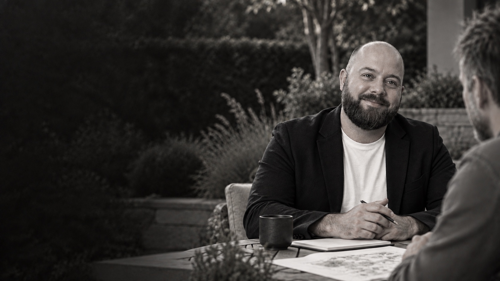 KI-generiertes Markenmotiv: Jan Matzen im Gespräch mit einer fiktiven Person auf einer Gartenterrasse